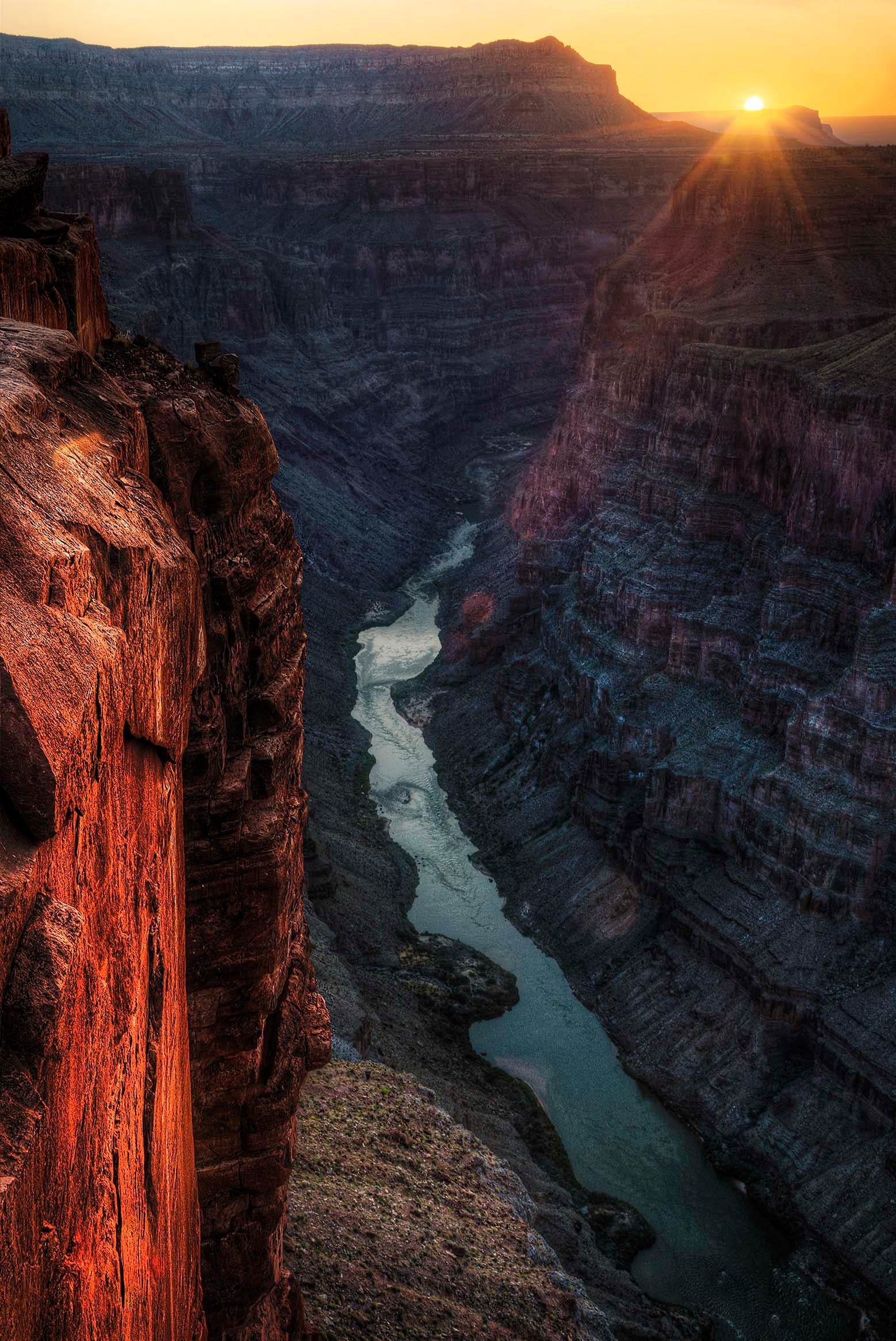 Dawn light breaking over the Grand Canyon from Toroweap Point, the Colorado River a silver thread far below