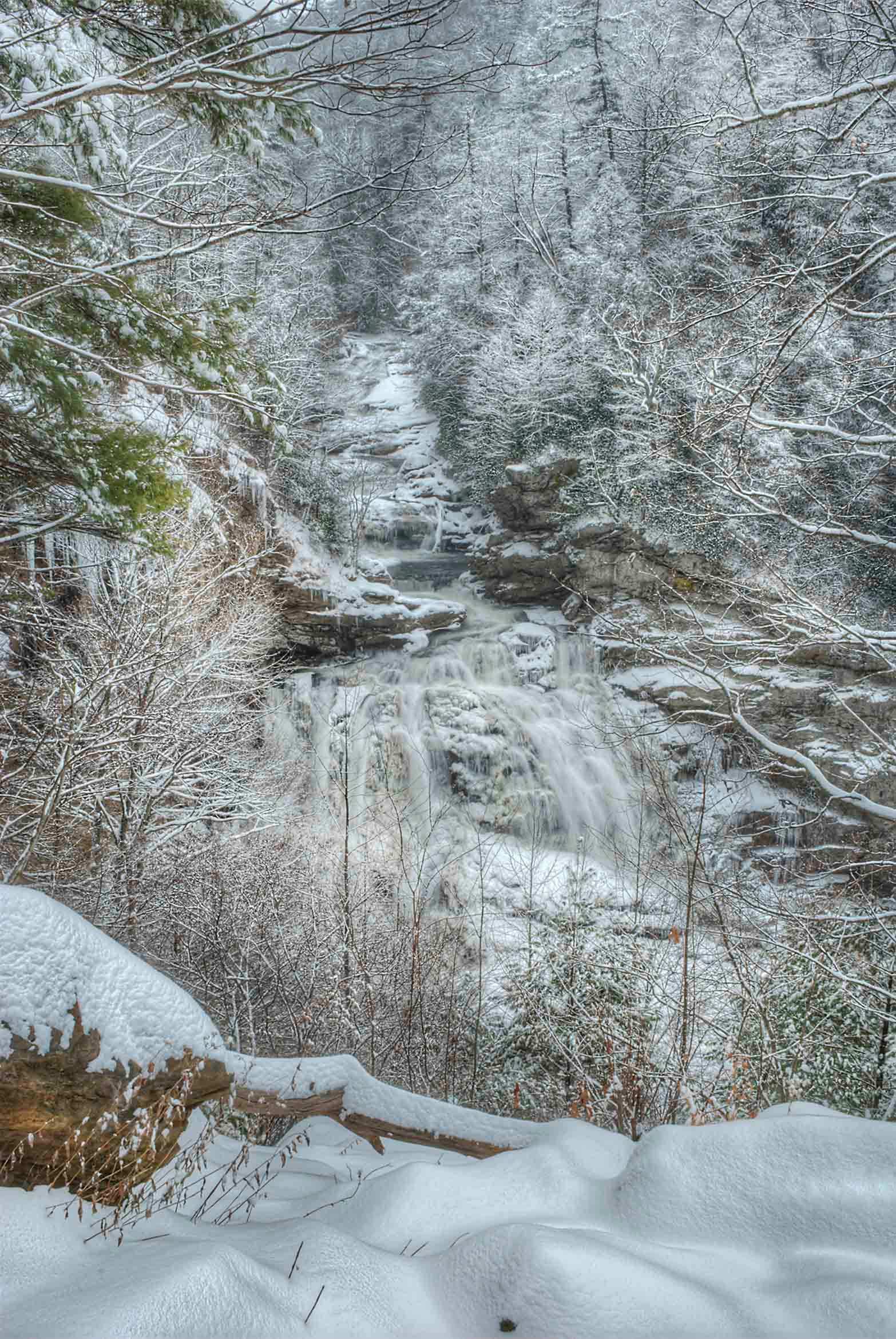 Frozen waterfall cascading over snow and ice-covered rock ledges in the Cullasaja Highlands