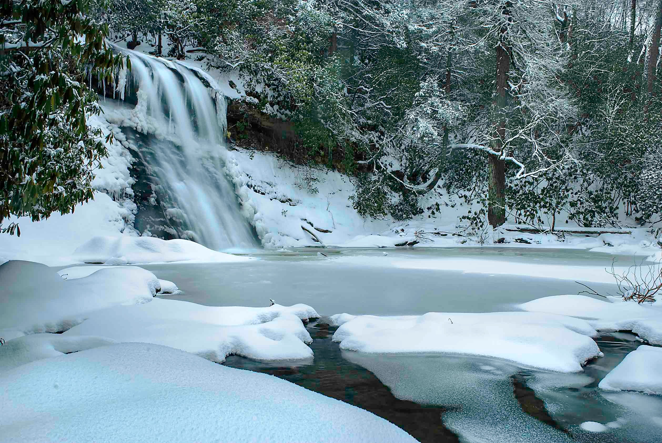 Silver Run Falls cascading over snow and ice-covered rocks in a winter forest