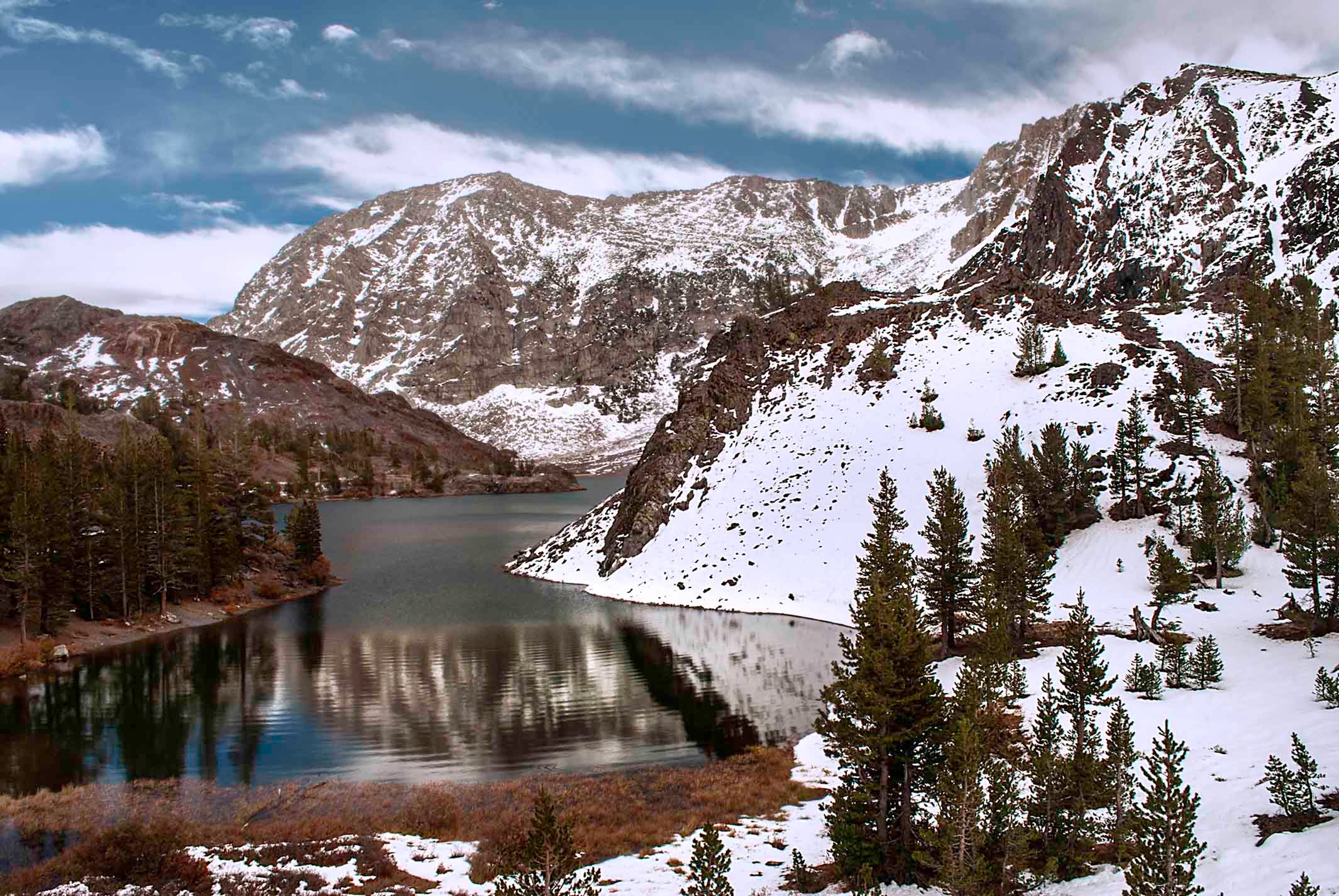 Snow-dusted peaks and alpine lake at Tioga Pass in the Sierra Nevada under a cloudy sky