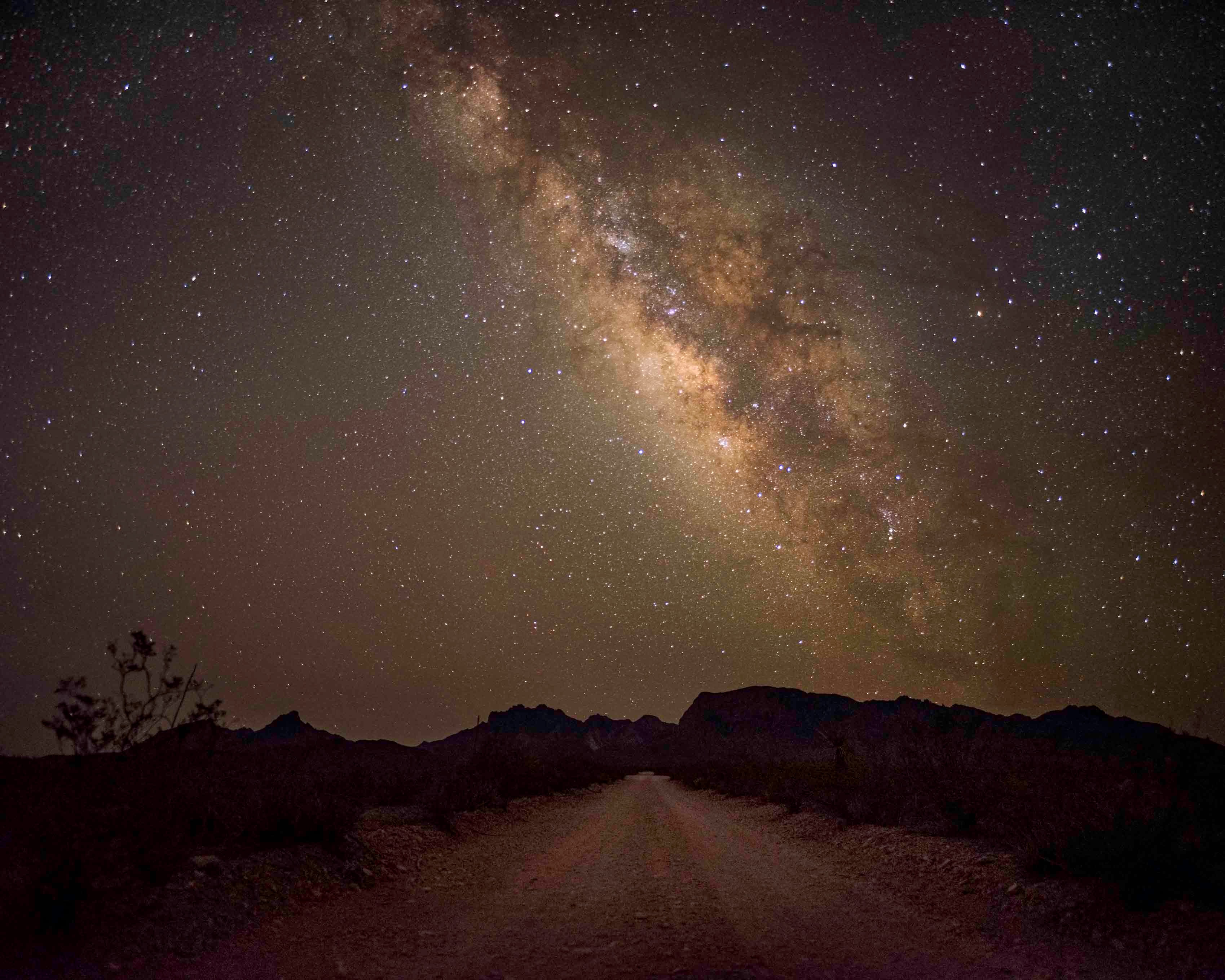 Milky Way over a desert dirt road leading toward the Chisos Mountains