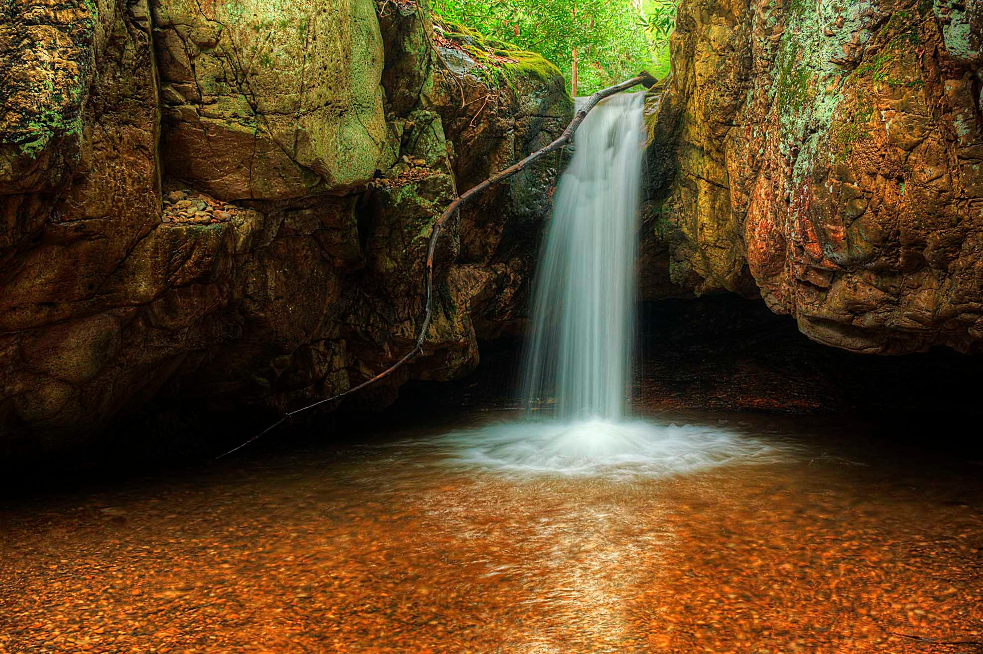 Middle Blue Hole Falls dropping in a single plunge into a glowing amber pool between ancient moss-covered canyon walls